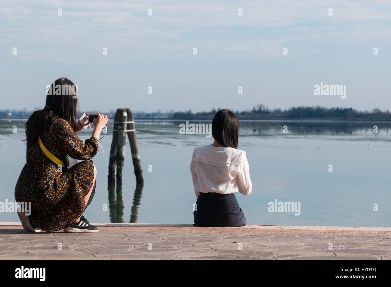 I turisti fare foto lungo la costa dell'isola di Burano, Venezia, Italia. Foto Stock