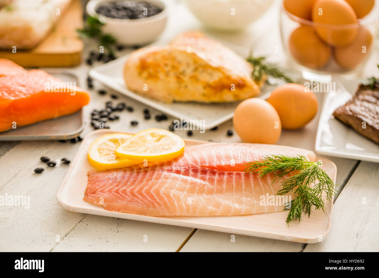 Pesce di tilapia crudo su piatto, pollo e uova sullo sfondo Foto Stock