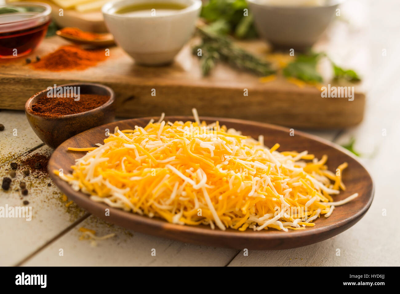 Formaggio grattugiato su piastra di legno Foto Stock