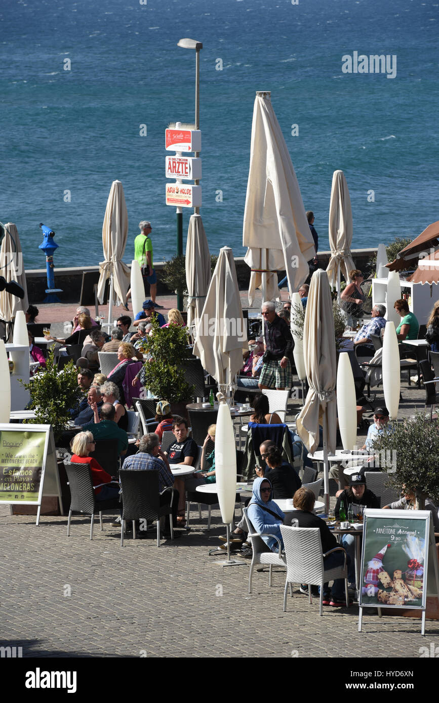 Porto via proprio accanto al mare in una giornata di vento con ristorante chiuso ombrelloni ma pieni di gente, tra Natale e Capodanno Gran Canarie Foto Stock