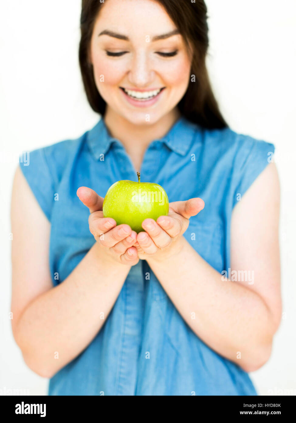 Donna che indossa la parte superiore blu che tiene la mela verde Foto Stock