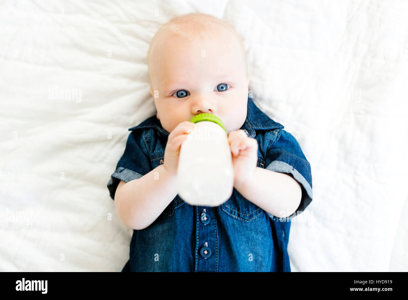 Bambino (12-17 mesi) sdraiato sulla schiena e bere latte in bottiglia Foto Stock