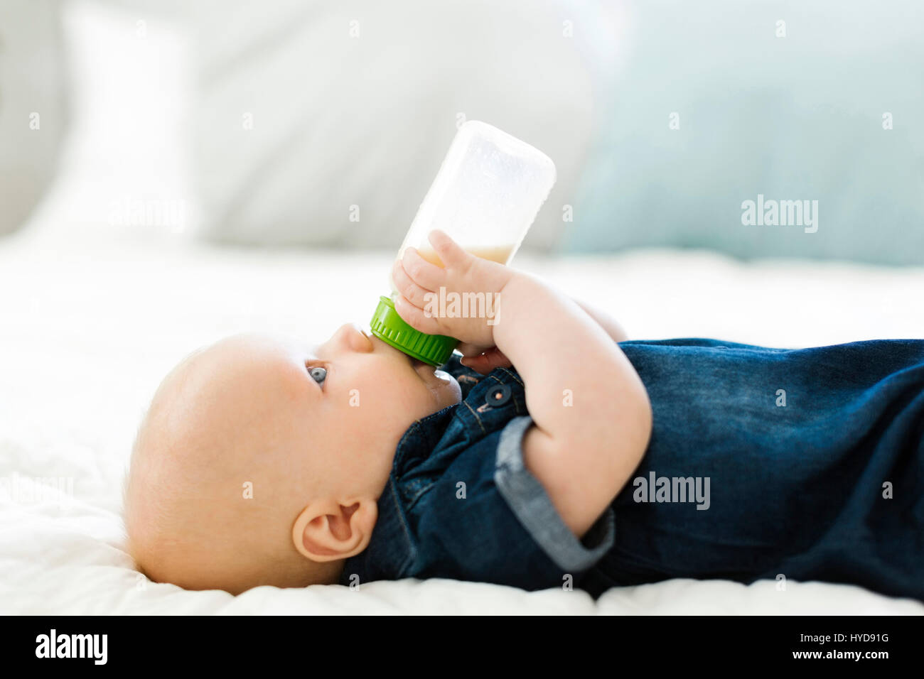 Vista laterale del bambino (12-17 mesi) bere il latte dal biberon Foto Stock