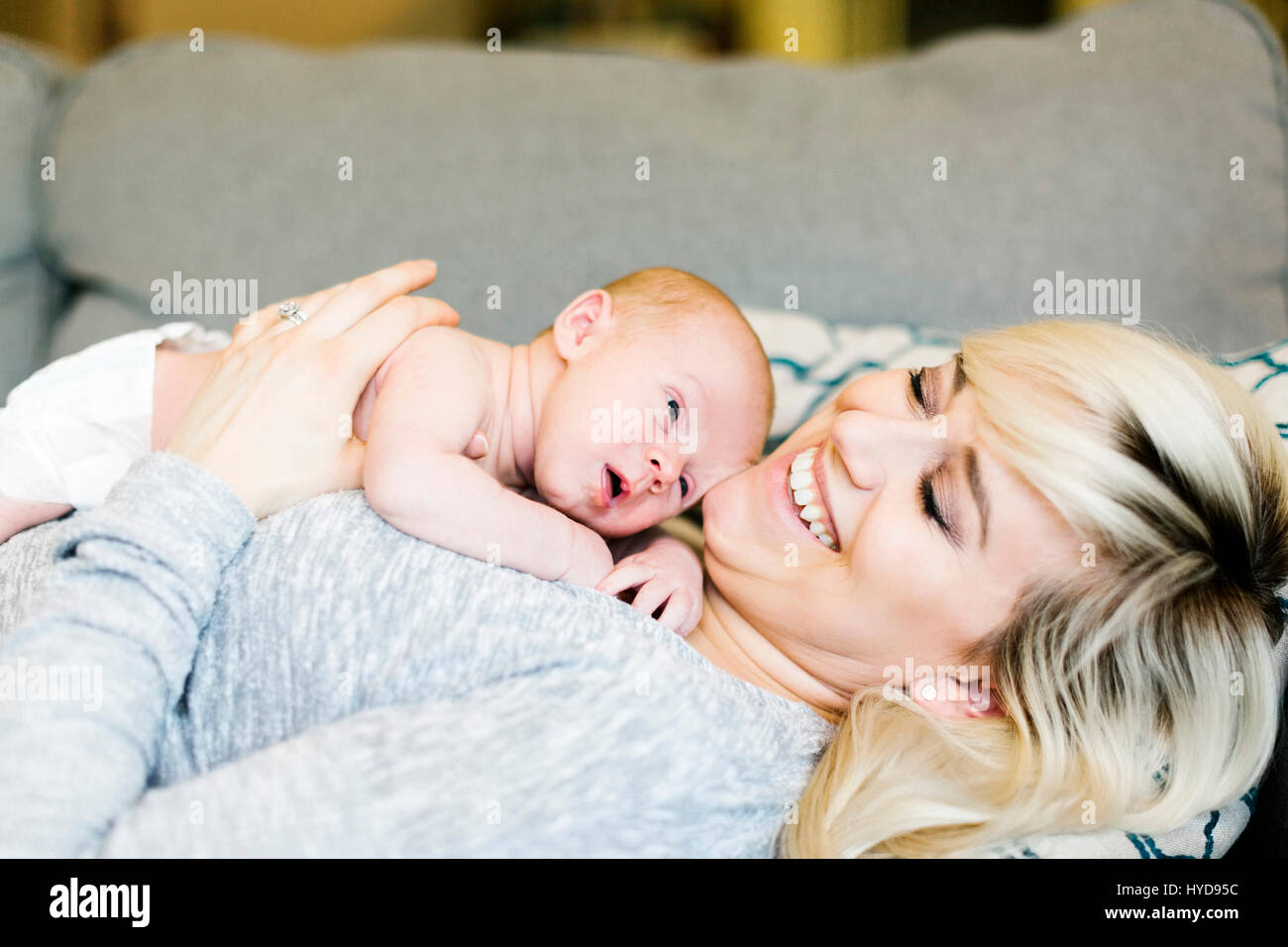 Madre giacente sul divano e tenendo il suo figlio di un giorno (0-1 mesi) Foto Stock