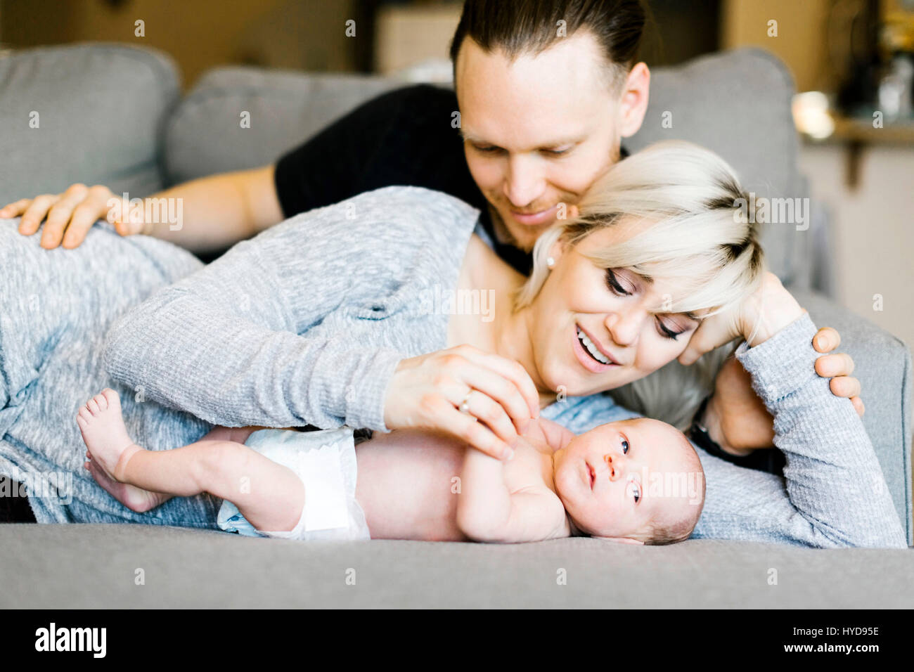 Famiglia con un figlio di un giorno (0-1 mesi) sdraiato sul divano Foto Stock