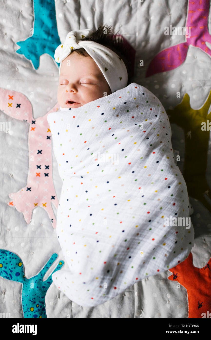 Bambina (0-1 mesi) avvolta in coperta dormendo sul letto Foto Stock