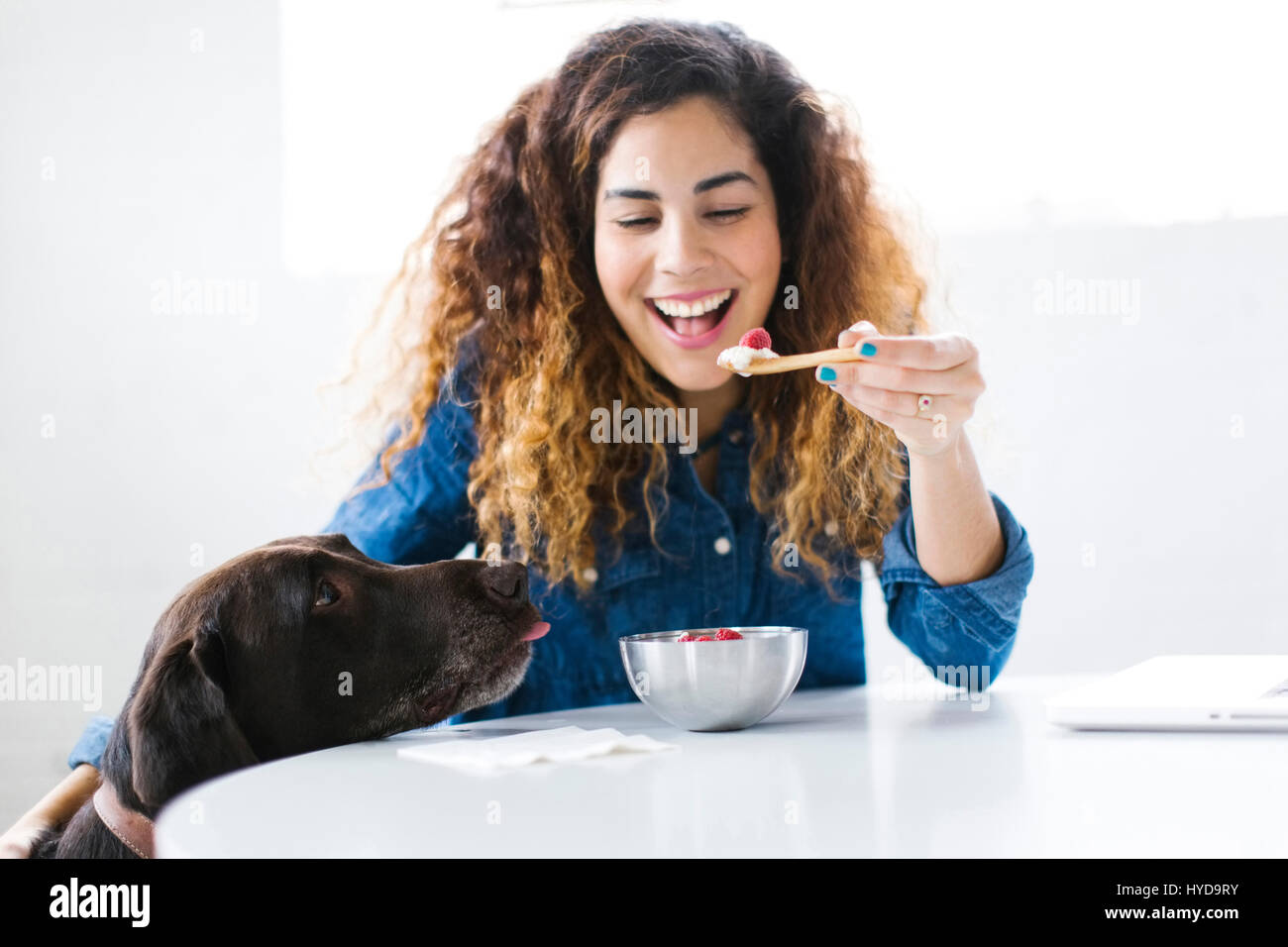 Donna con cane che mangia snack Foto Stock