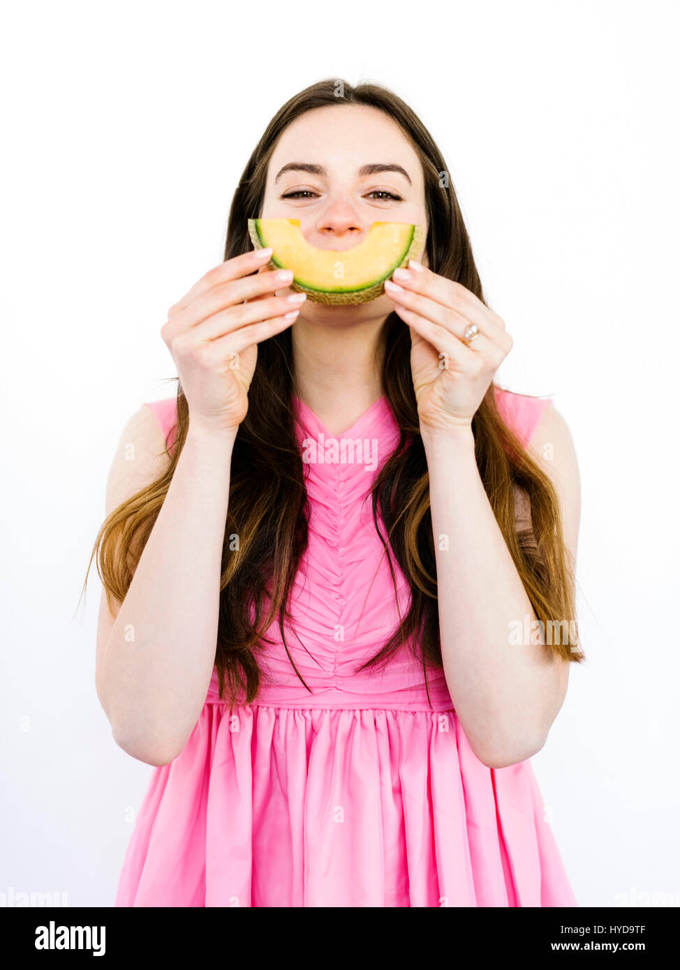 Donna che tiene una fetta di melone davanti alla bocca Foto Stock