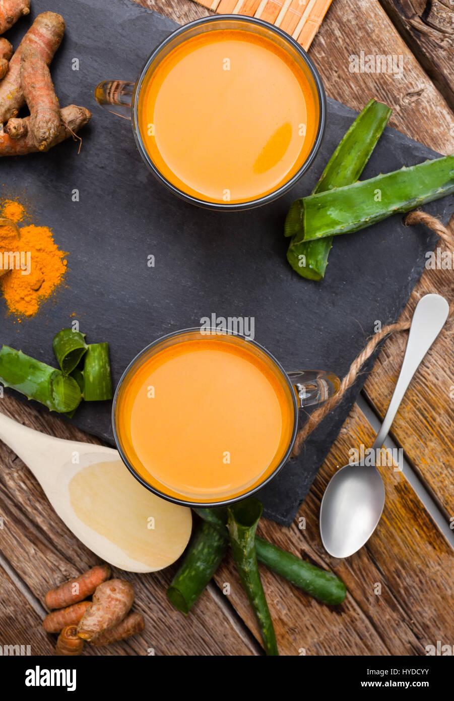 Bere aloe vera e la curcuma. Vista superiore delle coppe di vetro su un vassoio di ardesia Foto Stock