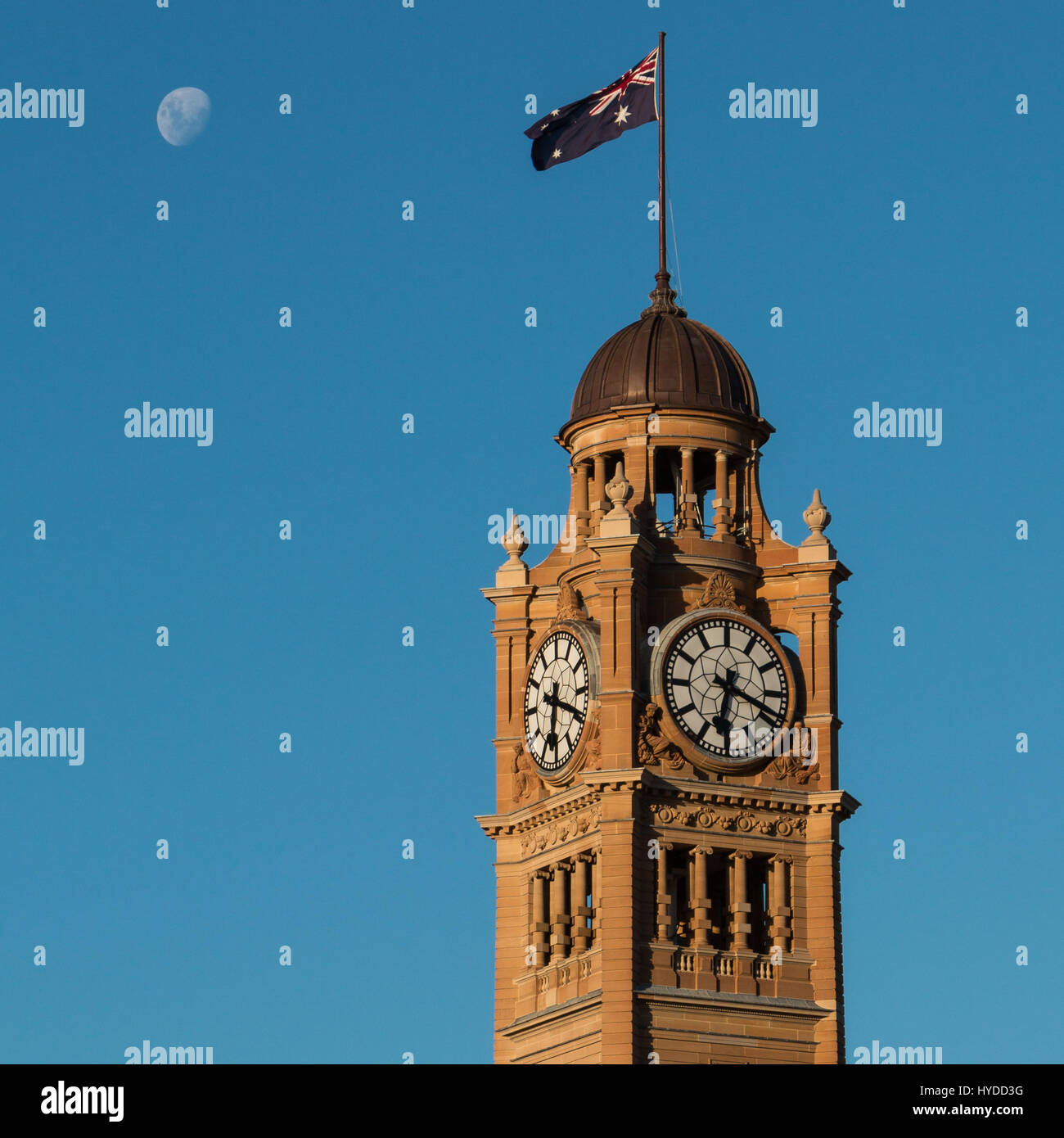 La torre dell'orologio della stazione centrale di Sydney con la bandiera australiana e la luna Foto Stock