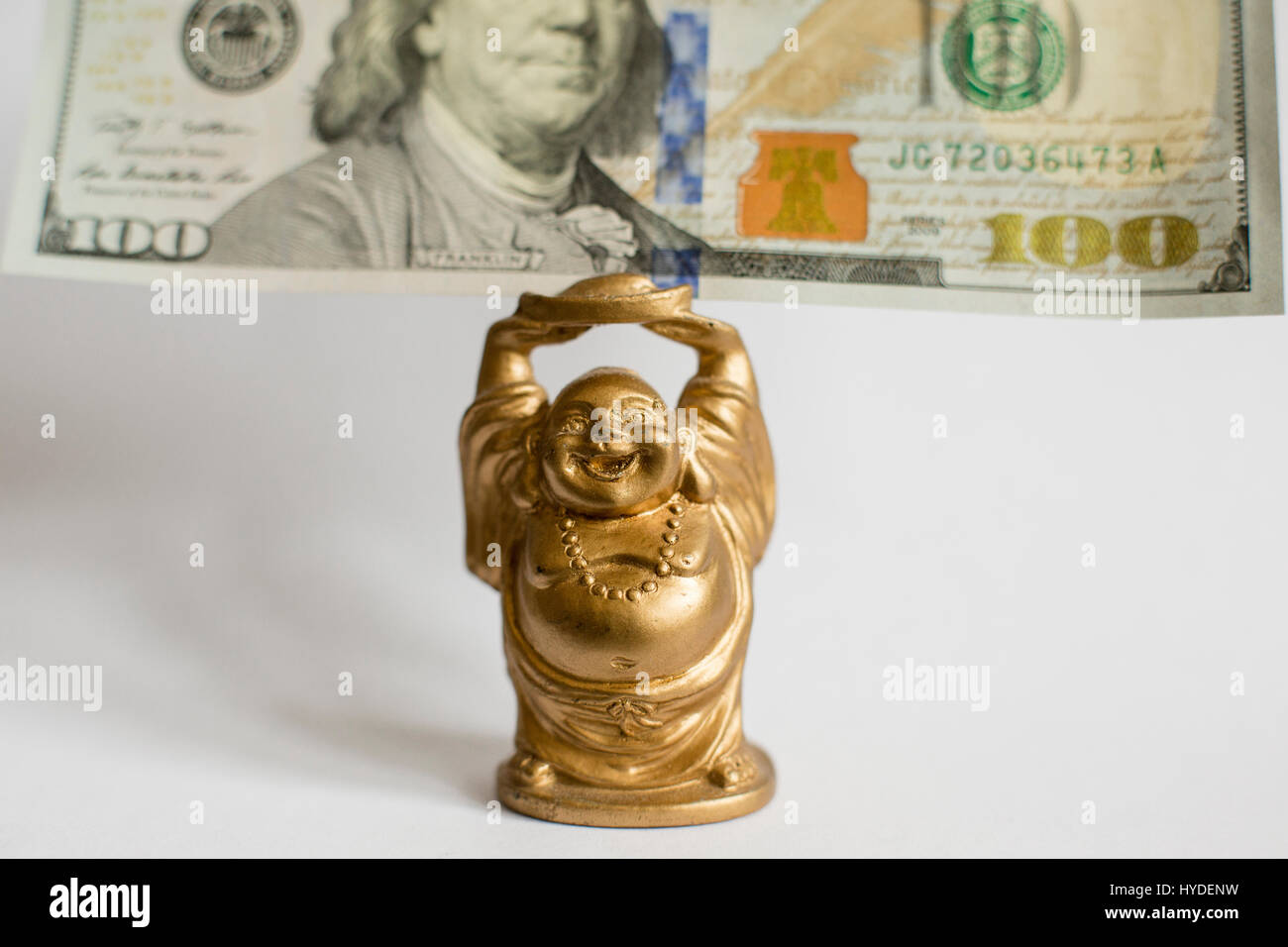 In prossimità di un piccolo golden BUDDA STATUETTA tenendo un centinaio di dollari in valuta degli Stati Uniti sopra la sua testa Foto Stock