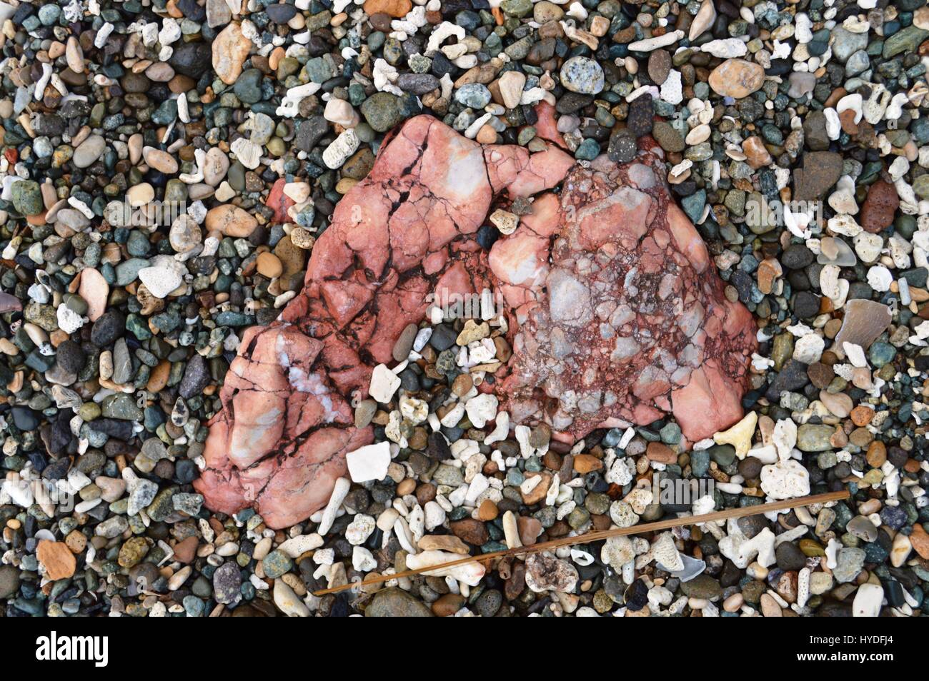 Una miscela di pietre e bit di corallo attorno a una rosa di roccia metamorfica lungo la spiaggia vicino Suminabang grotte a Caranan, Pasacao, Cam Sur, Filippine. Foto Stock