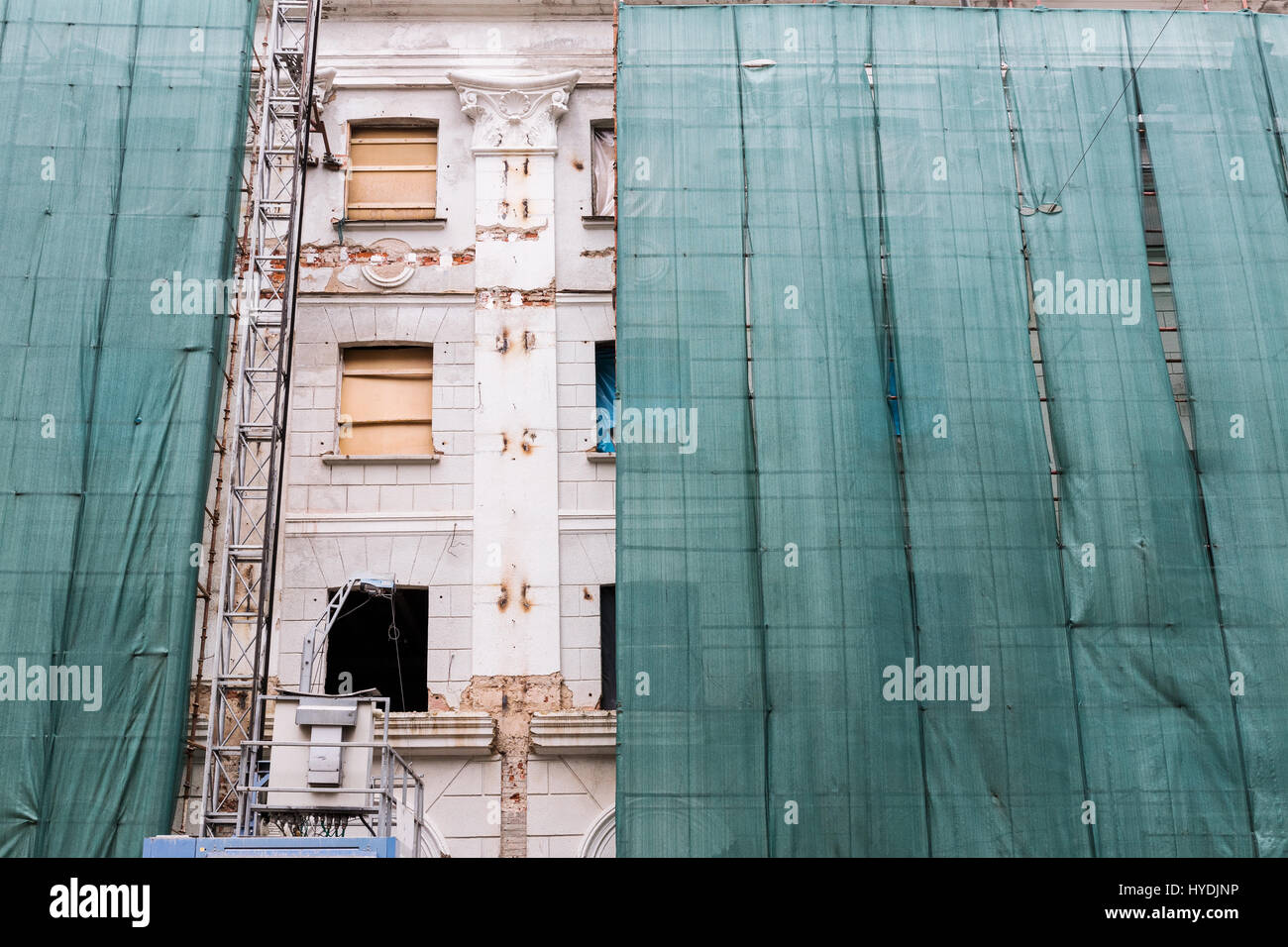 Il vecchio edificio cittadino con pareti a spiovente durante la ricostruzione con verde maglia protettiva Foto Stock