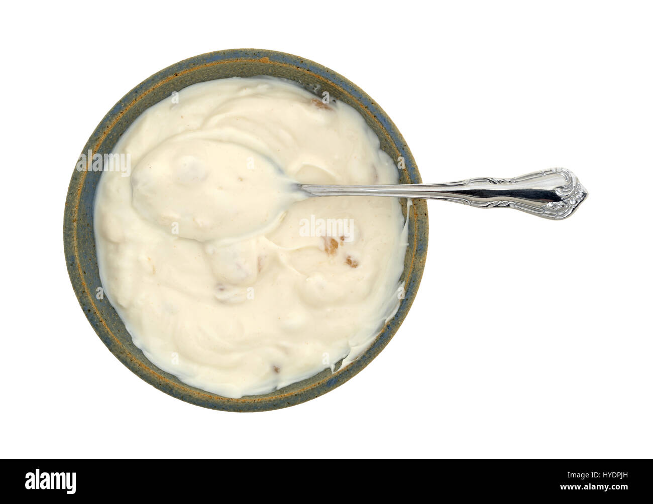 Vista superiore di apple vaniglia yogurt greco in un vecchio recipiente di ceramica con un cucchiaio nel cibo isolato su uno sfondo bianco. Foto Stock