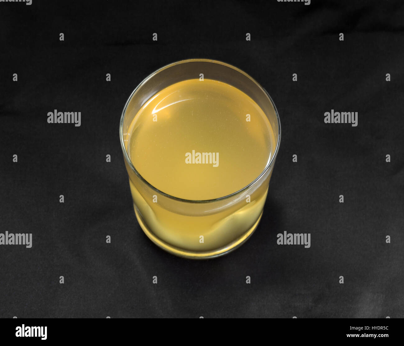 Un bicchiere pieno di acqua di cocco su un panno nero lo sfondo. Foto Stock