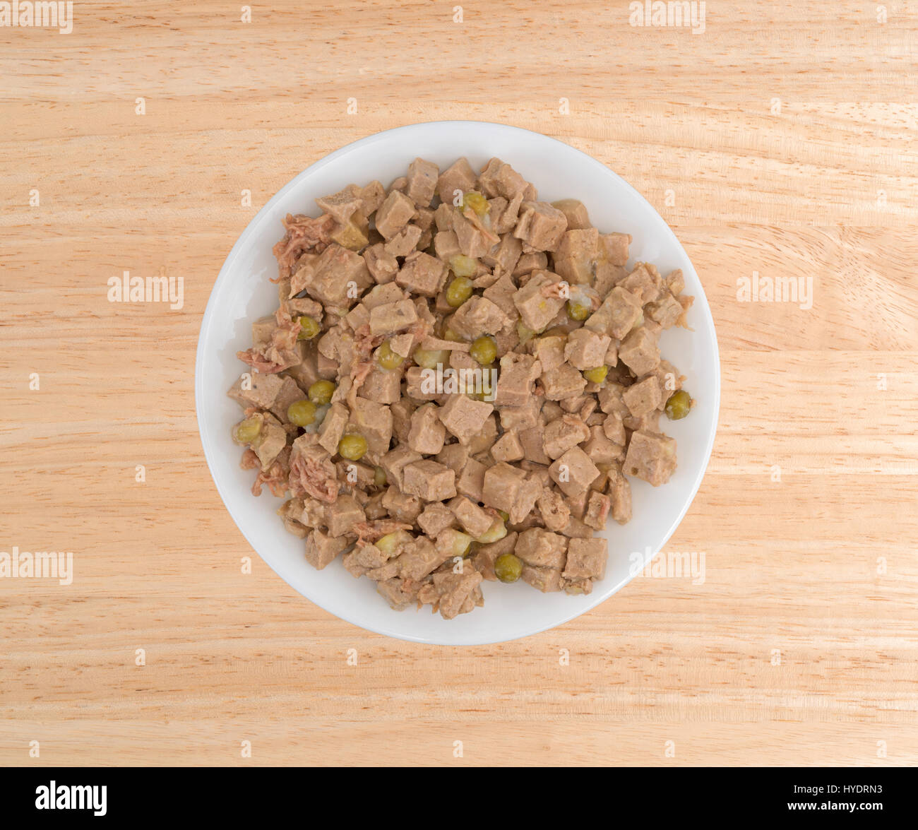 Vista dall'alto di un agnello e anatra con verdure gourmet dog food su una piastra bianca in cima a una tavola di legno. Foto Stock