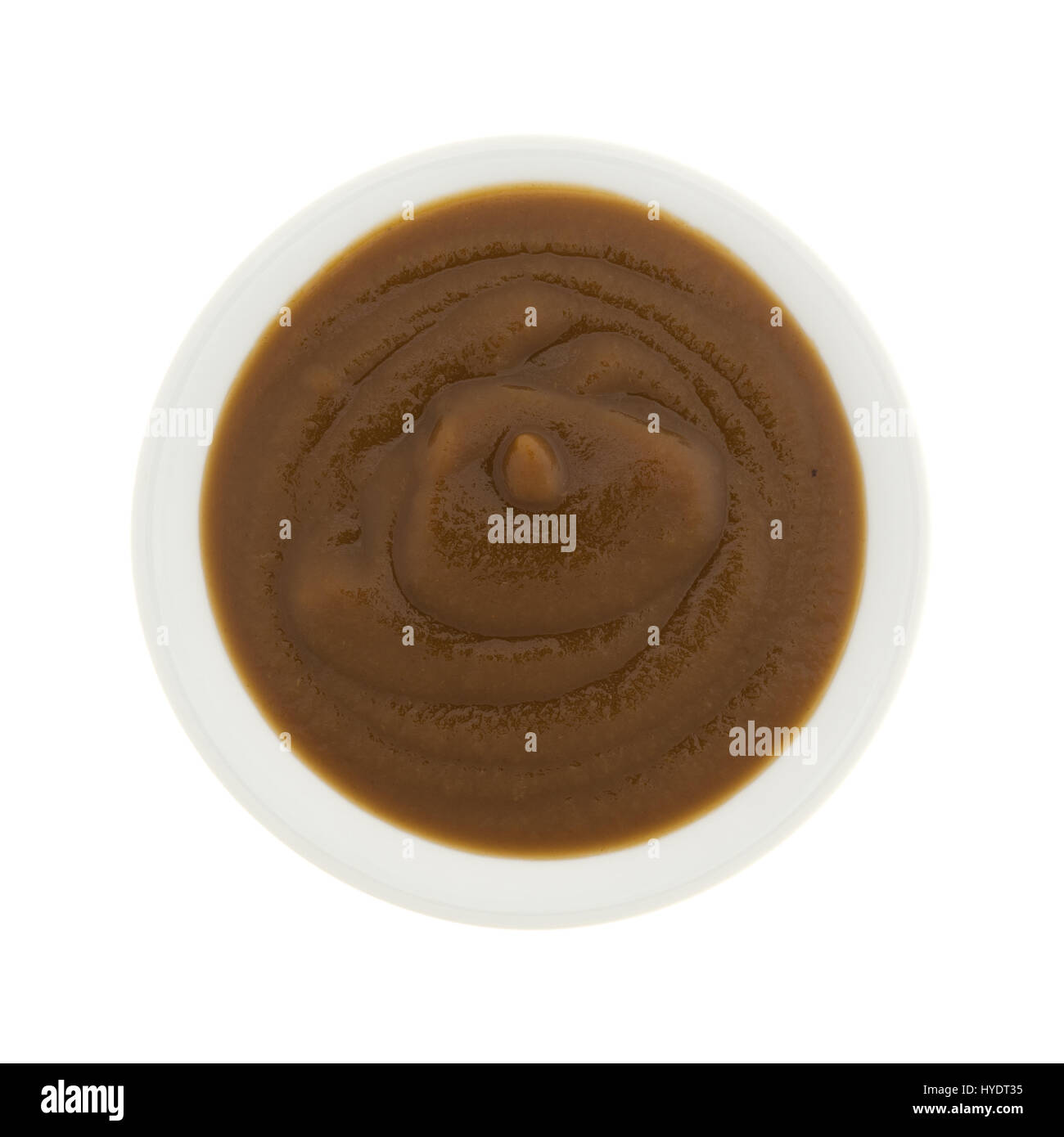 Vista dall'alto di una piccola ciotola bianco riempito con Apple e potare la purea di cibo per neonati isolato su uno sfondo bianco. Foto Stock