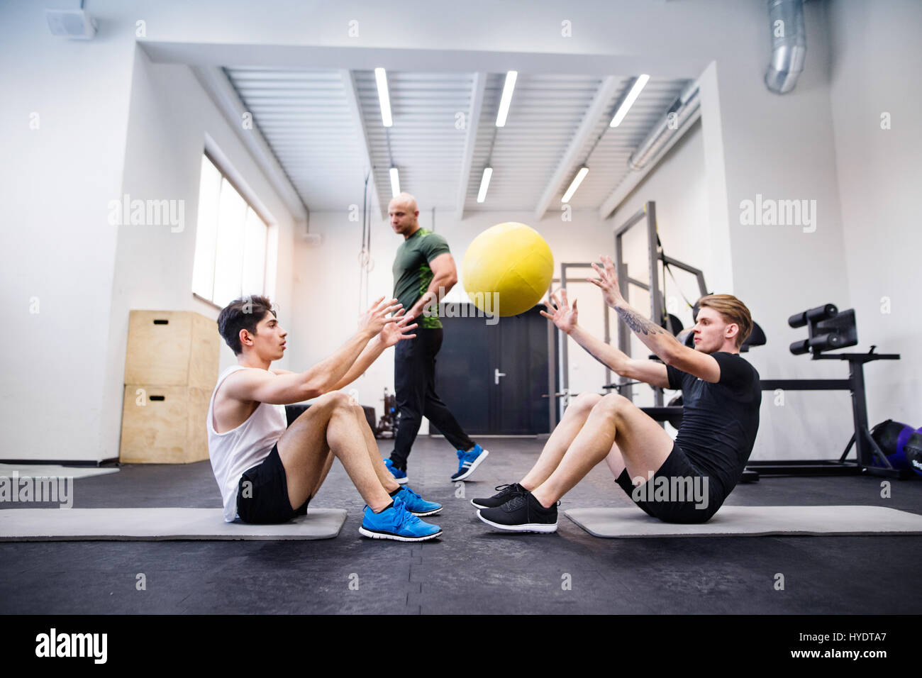 Uomini in palestra con trainer esercitando con sfere di medicina. Foto Stock