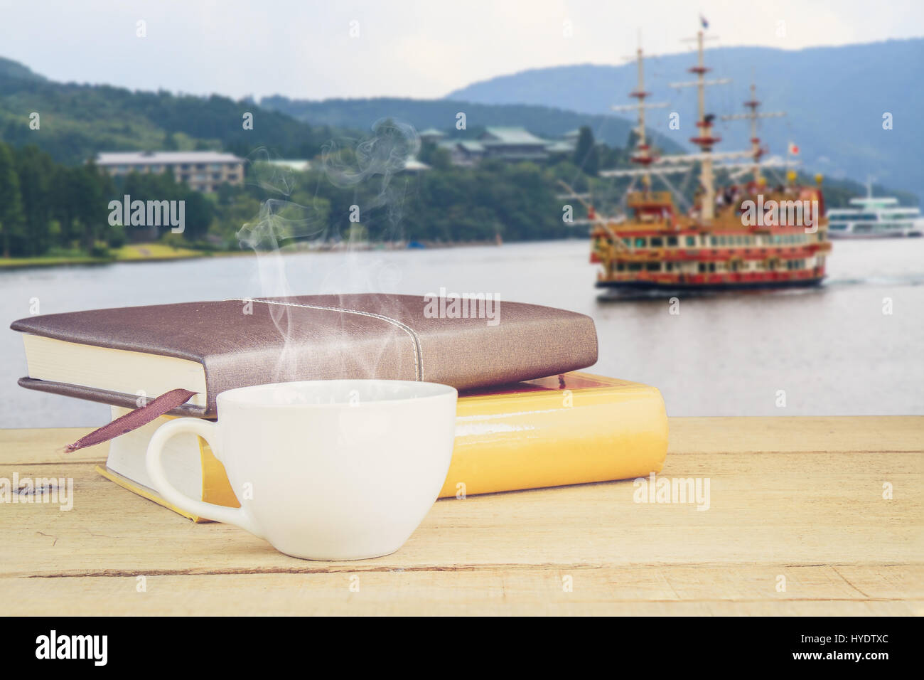 Caffè caldo e un libro sul tavolo in legno barca di sfondo nel lago Ashi Tokyo Giappone con copia spazio. concetto immagine. Foto Stock