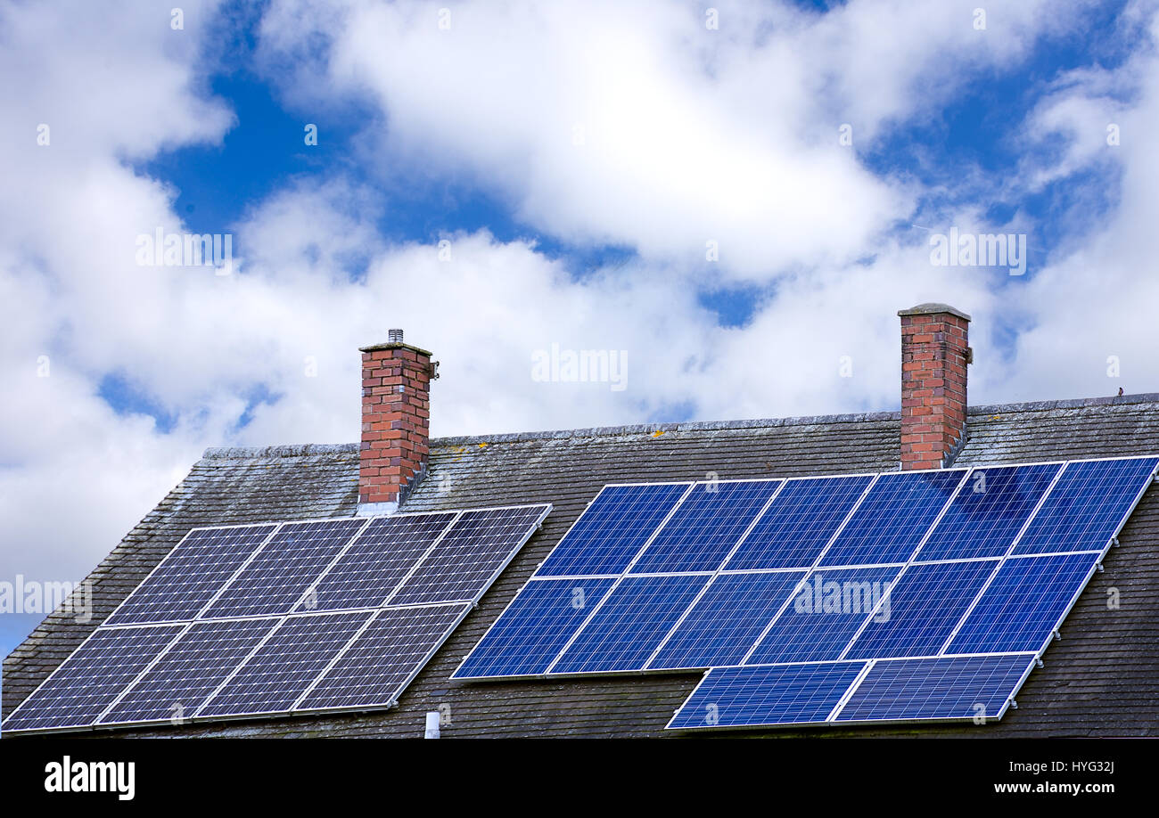 Fonte di energia rinnovabile e di pannelli solari sul tetto inclinato in alto con due camini, blu cielo con alcune nuvole in background,Stoke on Trent, Staffordshire, Regno Unito. Foto Stock