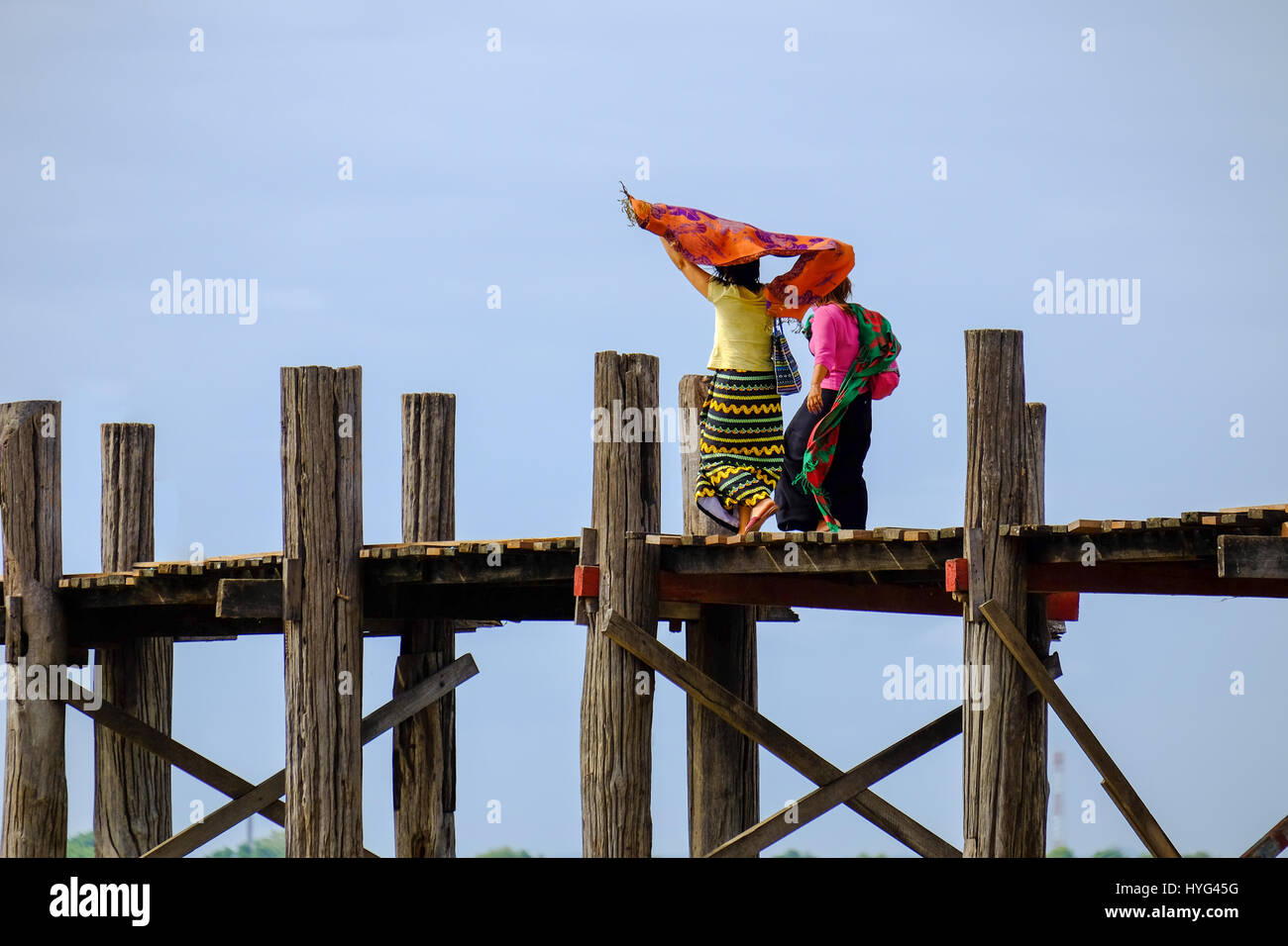 Due donne asiatiche in abiti colorati camminando sul ponte di legno, Amarapura, Mandalay Myanmar Foto Stock