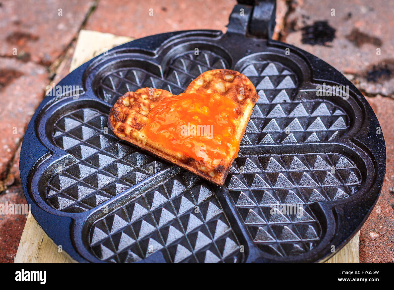 Singola cialda cuore con orange jam topping, giacente in waffle ferro da stiro Foto Stock