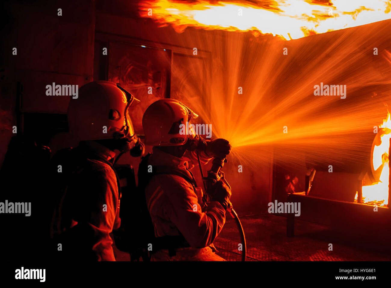 Vigili del fuoco effettuare live formazione antincendio e le tecniche di raffreddamento. Foto Stock