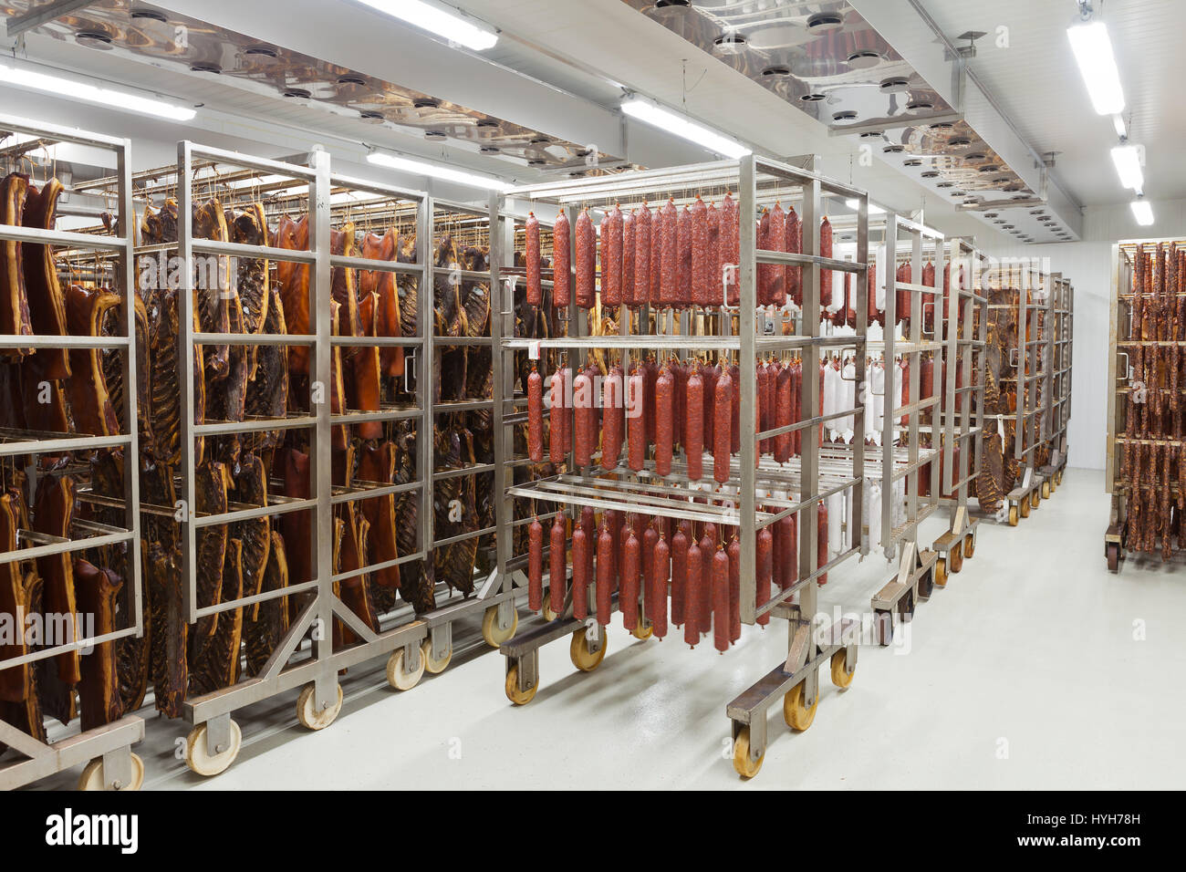 Fresche salsicce tradizionali pronti per essiccazione in un affumicatoio di una industria della carne Foto Stock