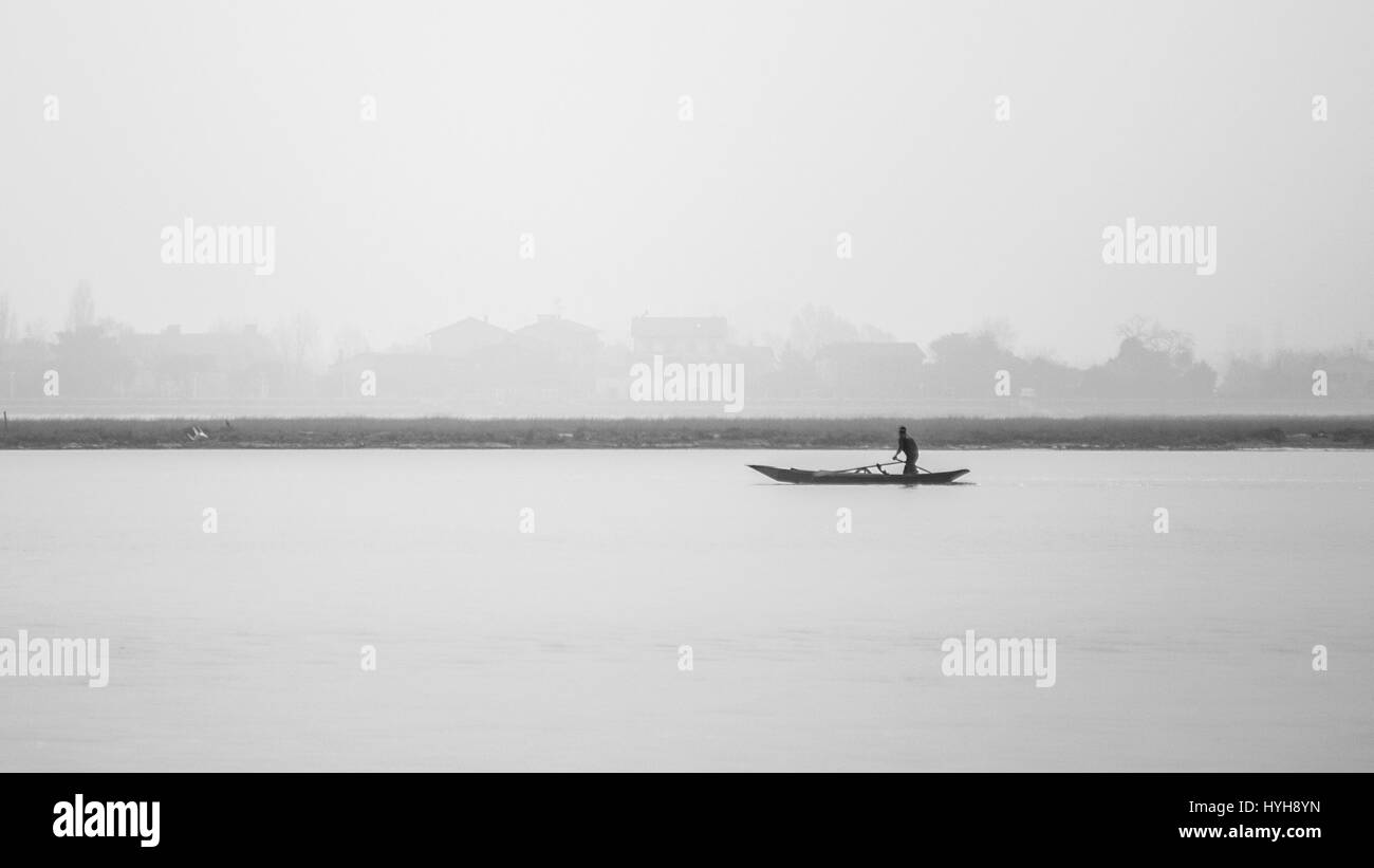 Un vogatore vela attraverso la laguna veneziana di fronte all'isola di Burano, Venezia, Italia. Foto Stock