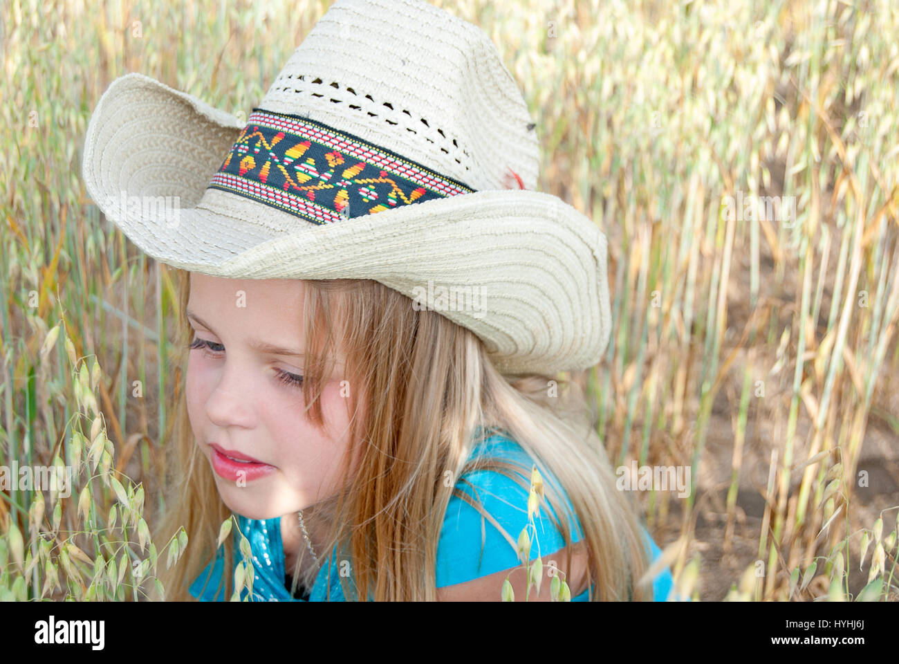 Giovane ragazza caucasica indossando western hat nel campo di grano Foto Stock