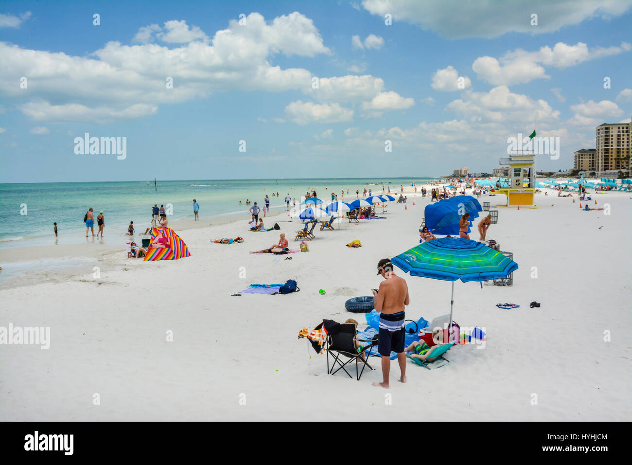 Vista di coloro che godono di sabbia bianca e acque turchesi di Clearwater Beach, FL, con il numero 5 la torre bagnino e cananas blu e ombrelloni e Foto Stock