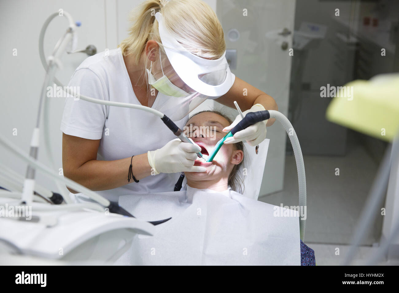 Donna in studio dentistico, dentista esaminando e pulizia i suoi denti del tartaro e della placca, prevenire la malattia periodontale. Igiene dentale, dolorose procedu Foto Stock