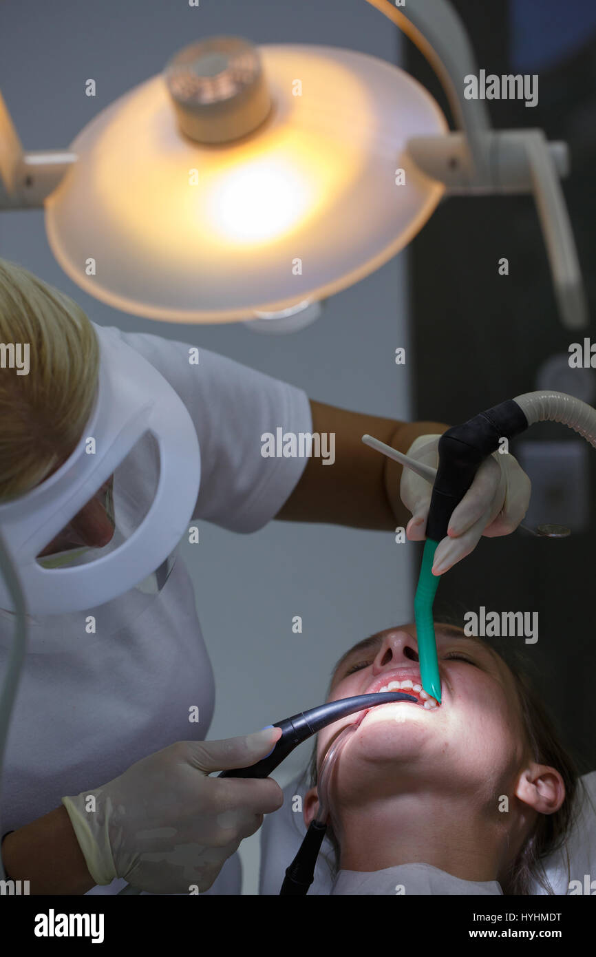 Paziente in studio dentistico con bib dentale, dentista esaminando denti, trattate per cavità, dato nuovo ripieni. Igiene dentale, procedure dolorose e pr Foto Stock