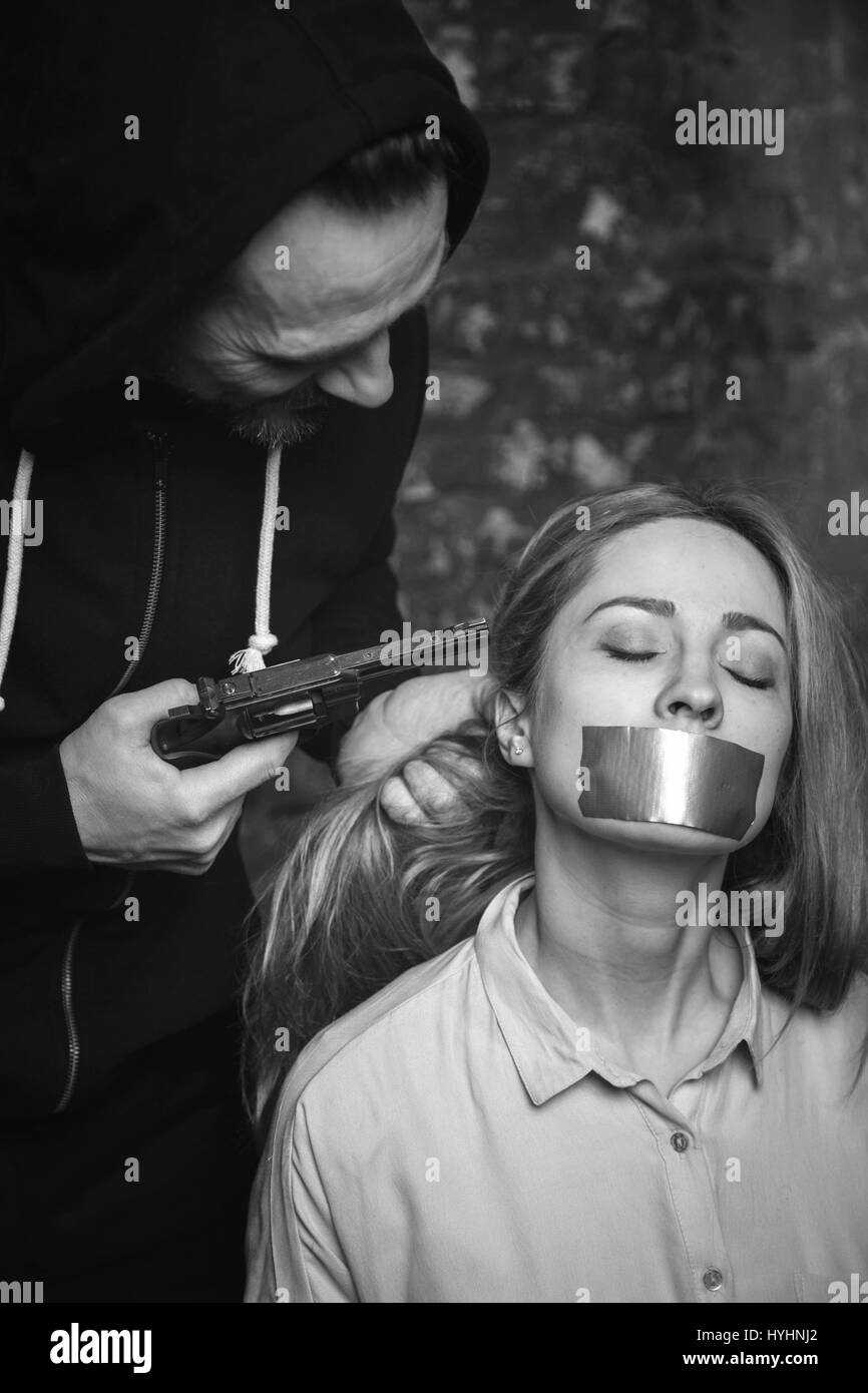 Violento criminale barbaro spaventare suo ostaggio con una pistola Foto Stock