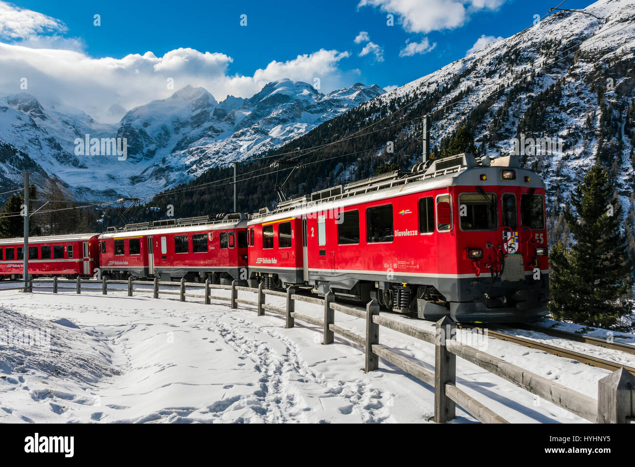 Vista invernale del Bernina Express il trenino rosso con il Bernina e Morteratsch ghiacciaio in background, Grigioni, Svizzera Foto Stock