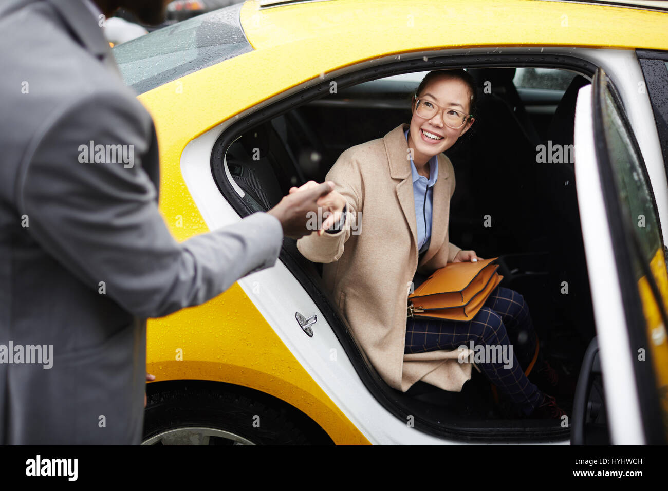 Gentleman aiutando giovane donna lasciare Taxi Foto Stock