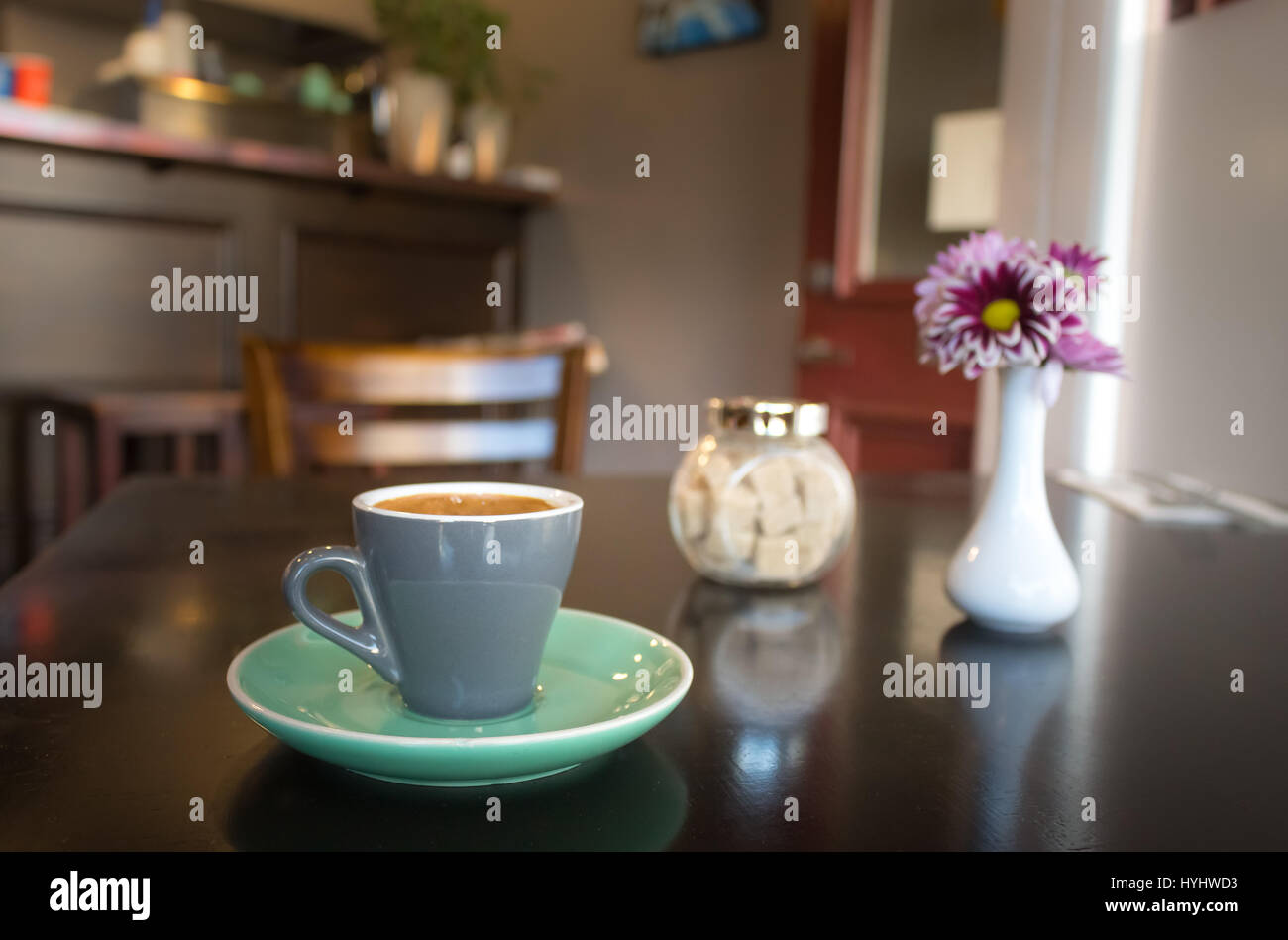 Semplice tazza di espresso con cubetti di zucchero e un fiore su un tavolo di legno. Foto Stock