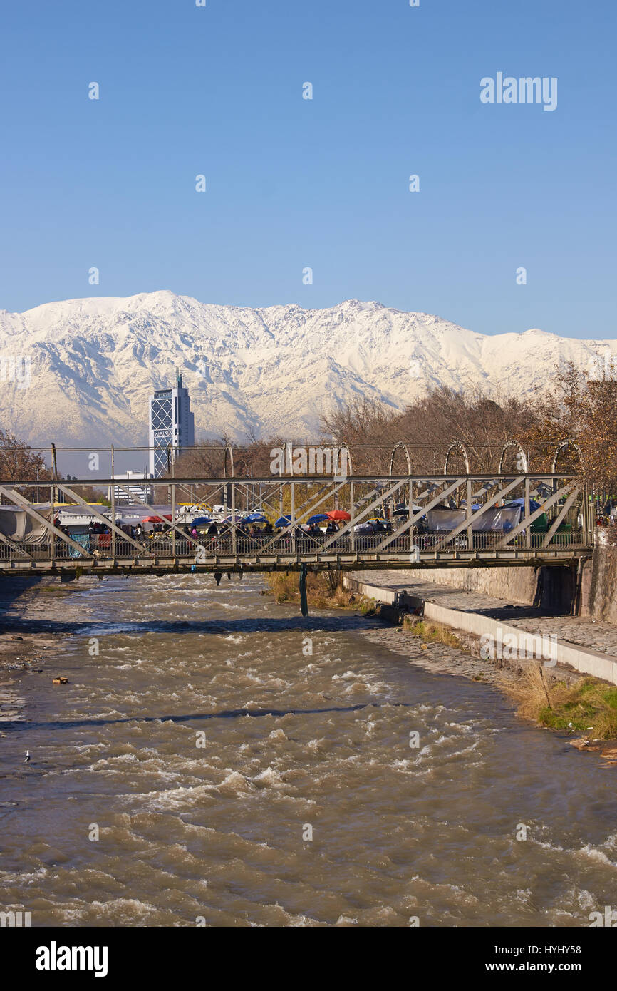 Montagne coperte di neve che circondano la città di Santiago, capitale del Cile. Vista da un ponte che attraversa il fiume Mapocho, nel centro di Santiago. Foto Stock