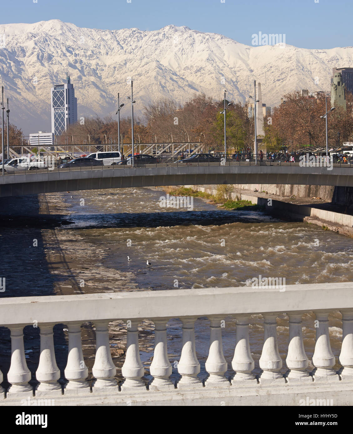 Montagne coperte di neve che circondano la città di Santiago, capitale del Cile. Vista da un ponte che attraversa il fiume Mapocho, nel centro di Santiago. Foto Stock