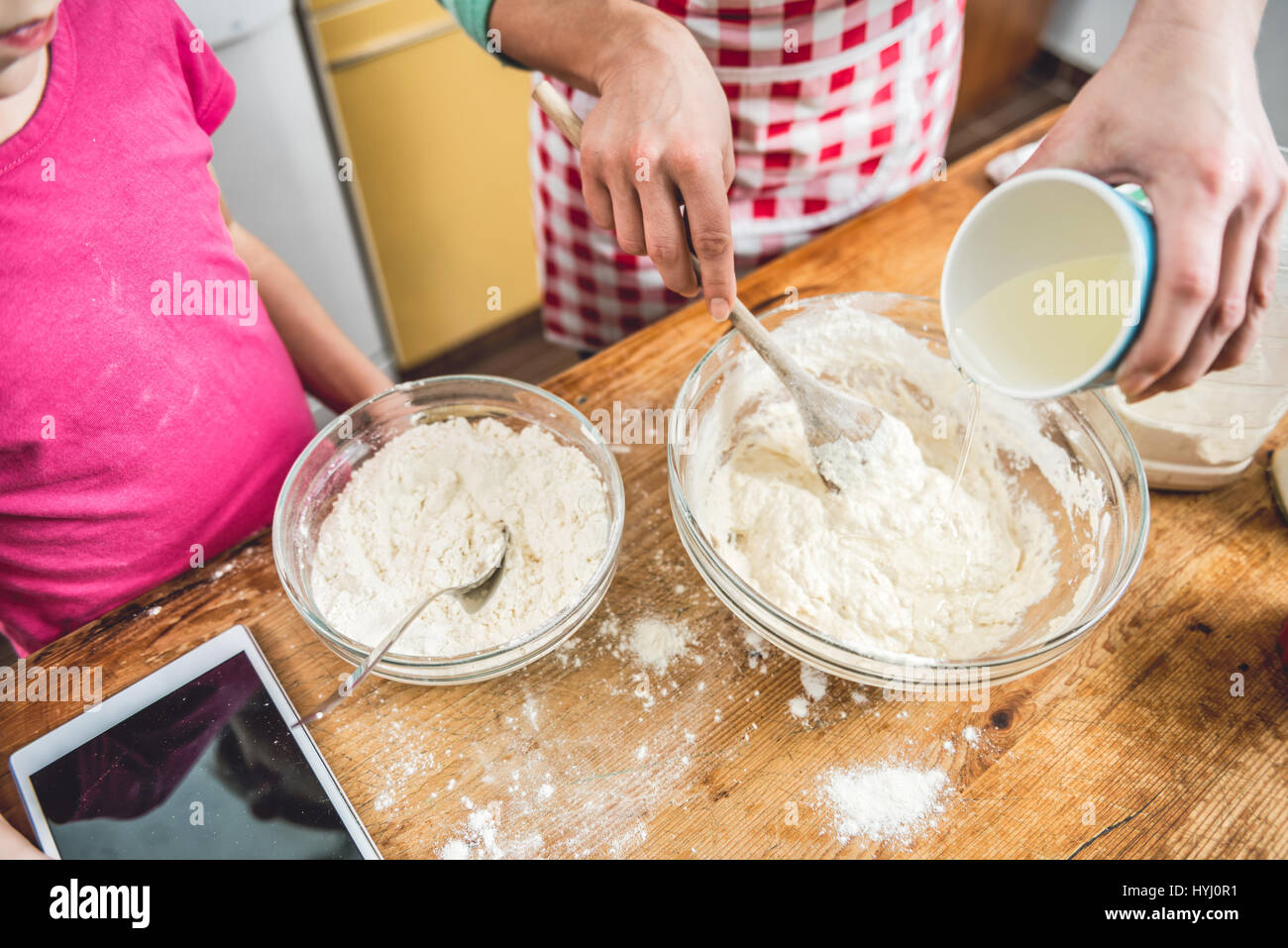 La figlia e la madre facendo impasto per pizza in cucina Foto Stock