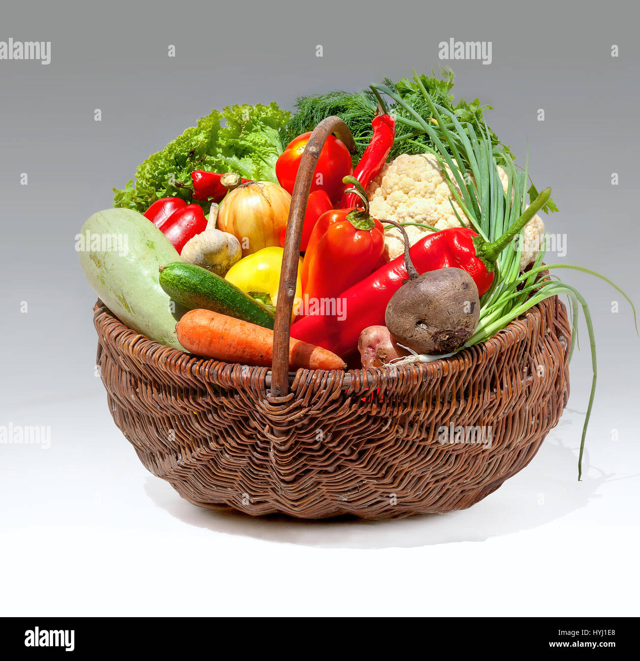 Heap colorati di verdure nel cesto in vimini su sfondo grigio Foto Stock