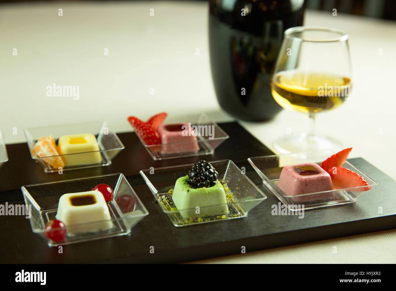 Caramelle gommose con frutta e cioccolata,un bicchiere di vino bianco Foto Stock