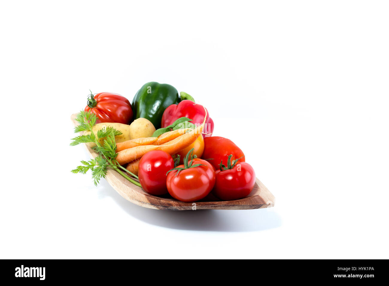 Le verdure in una naturale fatta a mano in vero legno bowl - Pomodori, carote, pepe, di fecola di patate Foto Stock