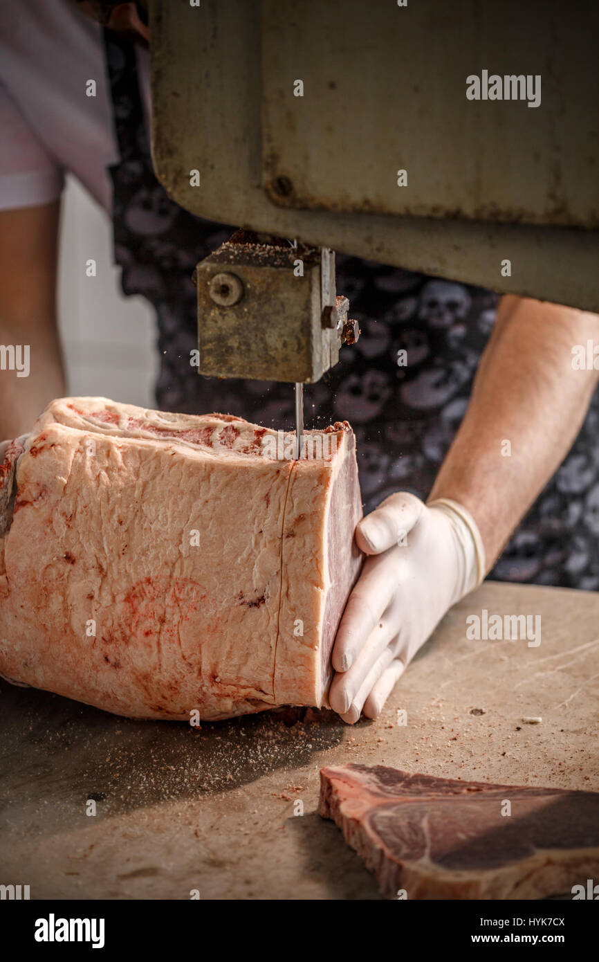 Lavoratore tagli su pezzi uguali carni bovine congelate Carni in work shop in fabbrica. Foto Stock