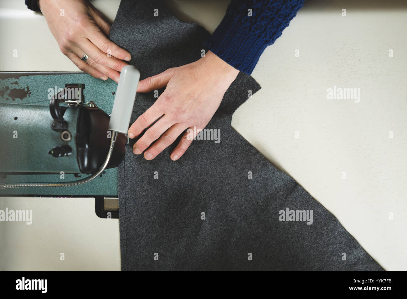 Mani di sarta cucitura con una macchina professionale di un tessuto grigio. Vista superiore Foto Stock