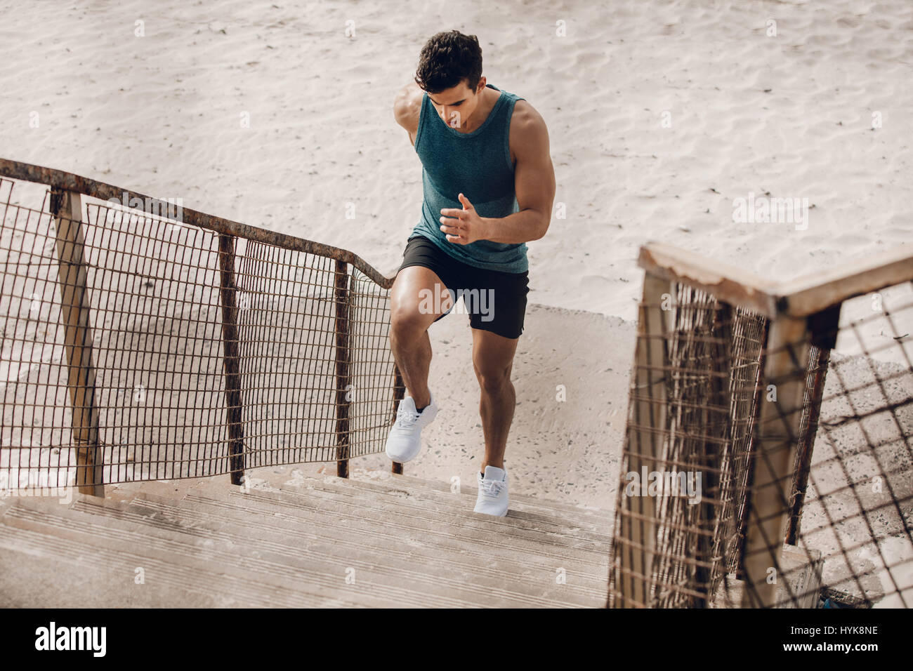 Muscolare di giovane uomo che esercitano sulla scala sulla spiaggia. Giovani runner salendo la scalinata sulla spiaggia. Foto Stock