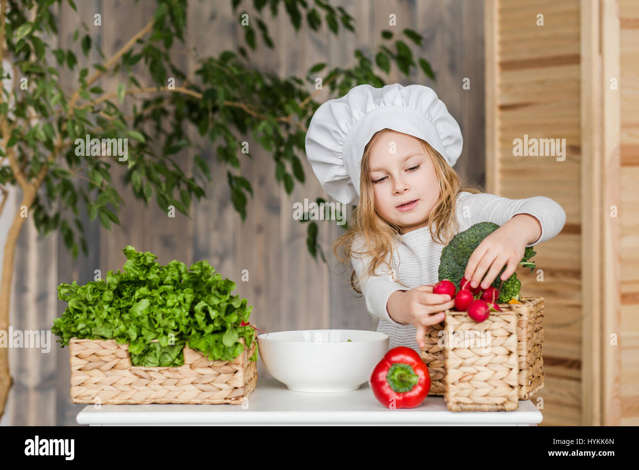 Poco bella ragazza rendendo insalata di verdure in cucina. Cibo sano. Poco casalinga Foto Stock