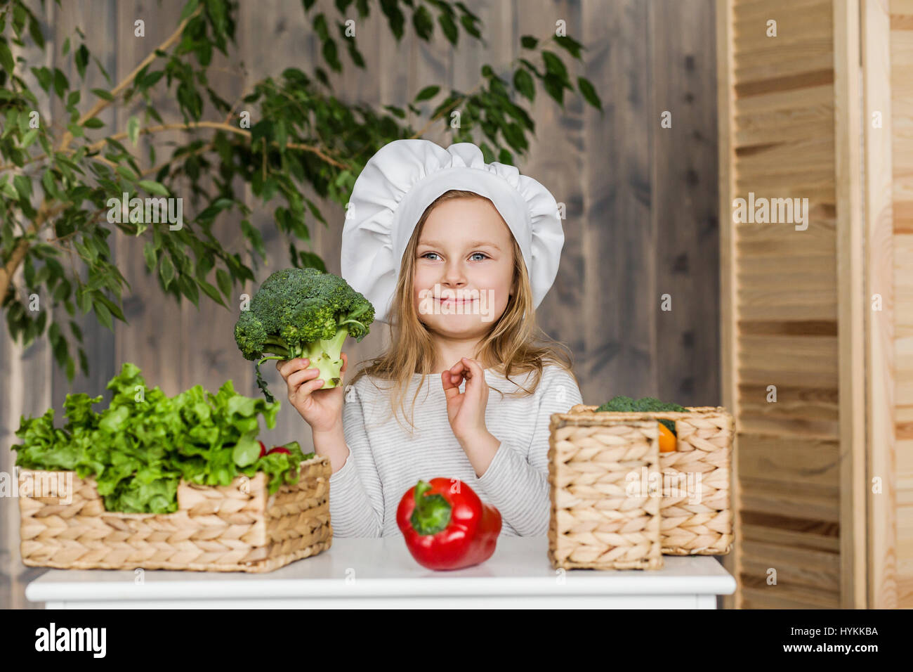 Poco bella ragazza rendendo insalata di verdure in cucina. Cibo sano. Poco casalinga Foto Stock