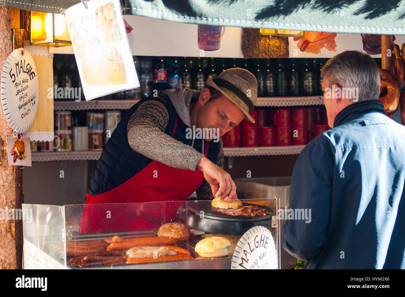 Un turista acquista un hot dog con i tradizionali mercatini di Natale di Bolzano, in Italia. Foto Stock