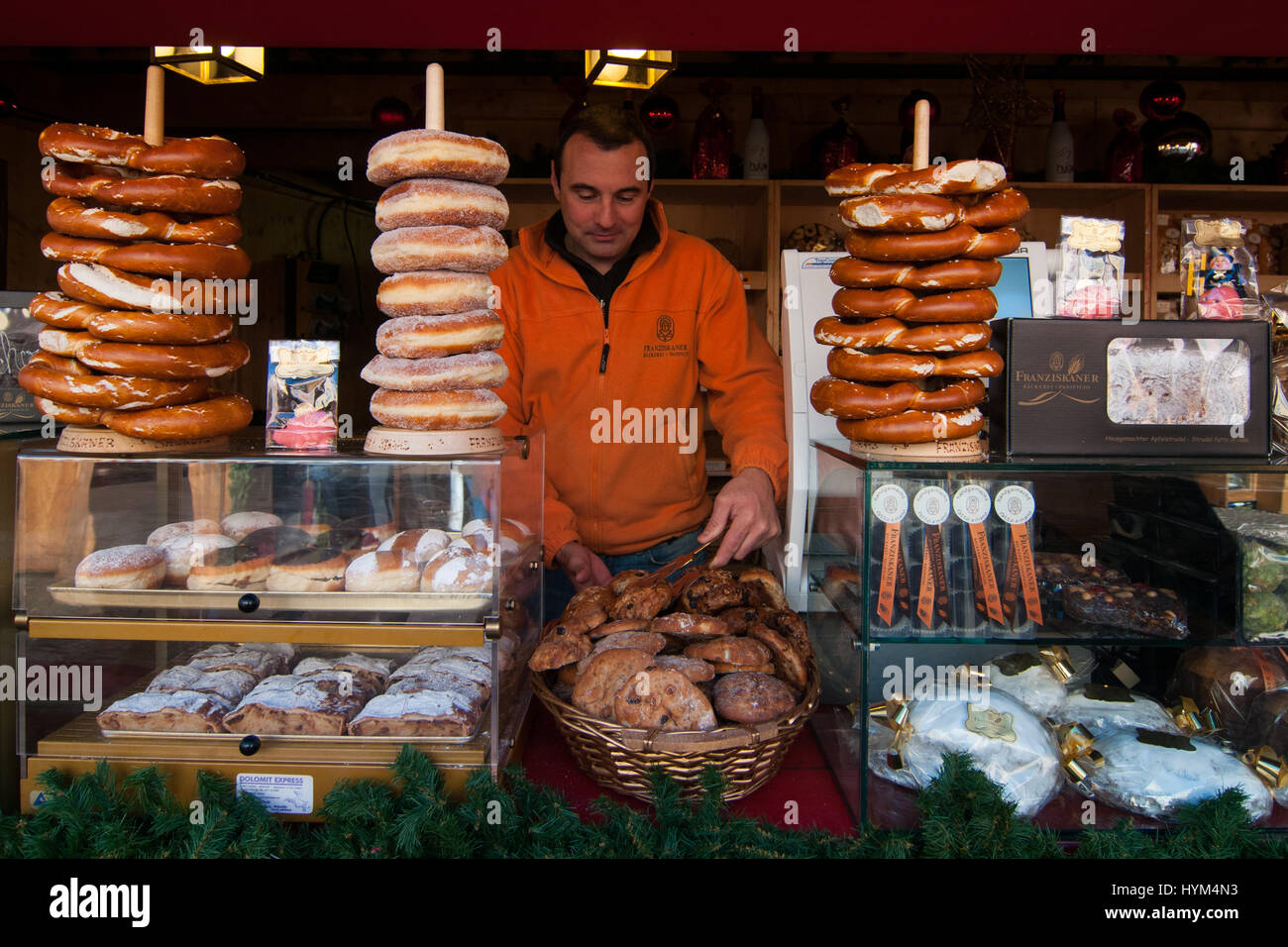 Un espositore nel suo stand di prodotti tipici presso i tradizionali mercatini di Natale di Bolzano, in Italia. Foto Stock